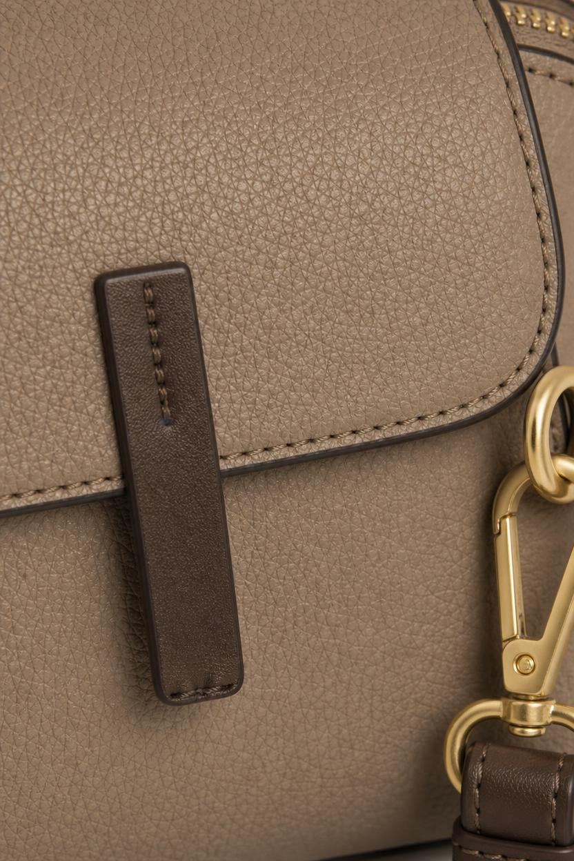 Detalle de la piel granulada del bolso Olli, la presilla de contraste y el mosquetón dorado